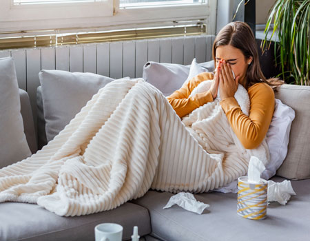 allegies Woman on sofa sneezing